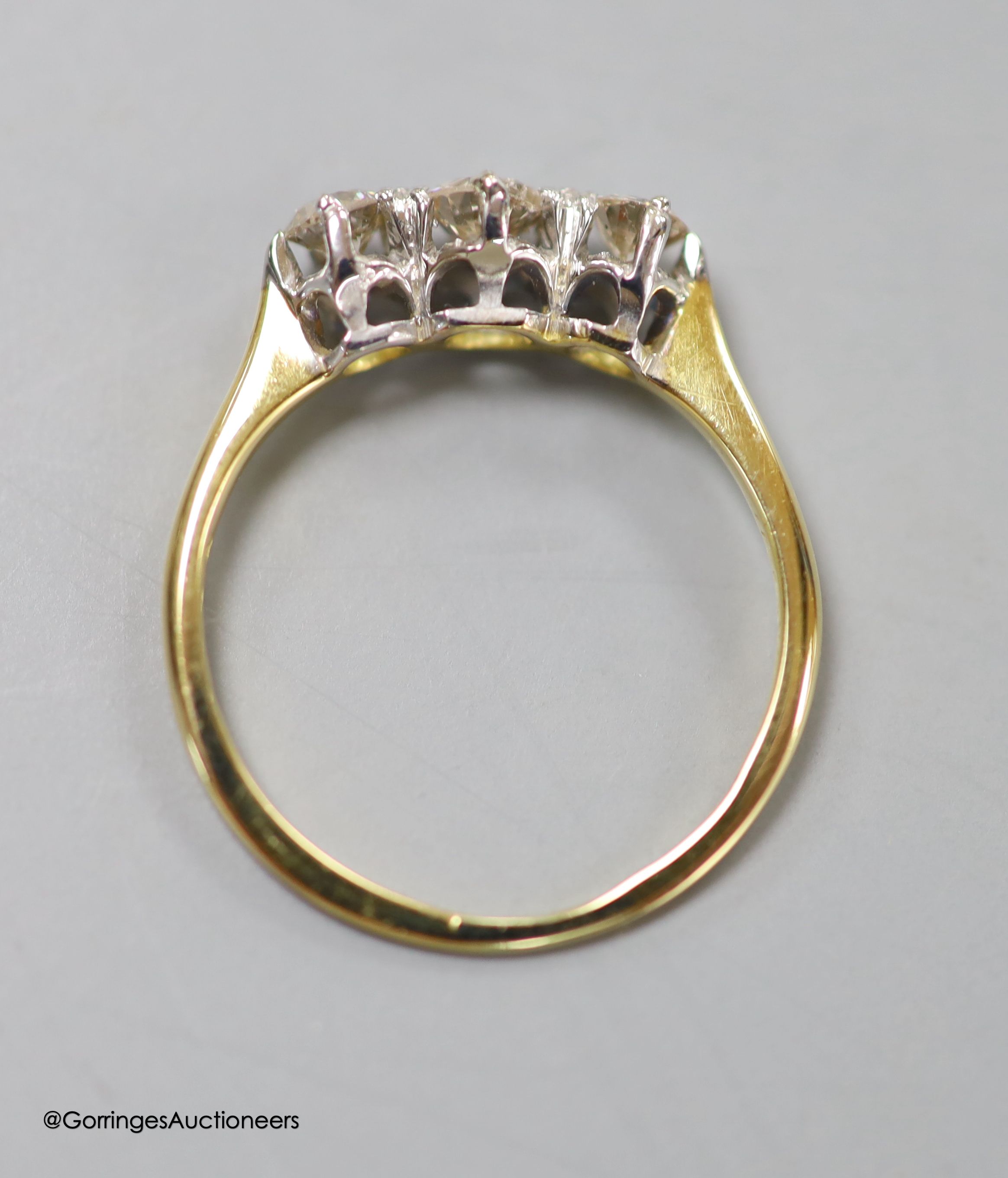 An 18ct and three stone diamond ring, size LM, gross 2.1 grams.